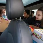 Cascade High senior Katerina Freeman, right, reaches for another box from Mariana Cardona and she and Harneet Aujla are buried under boxes in the back seat of a Mini Cooper during a food drive at Cascade High School on Wednesday, Dec. 14, 2016 in Everett, Wa. (Andy Bronson / The Herald)