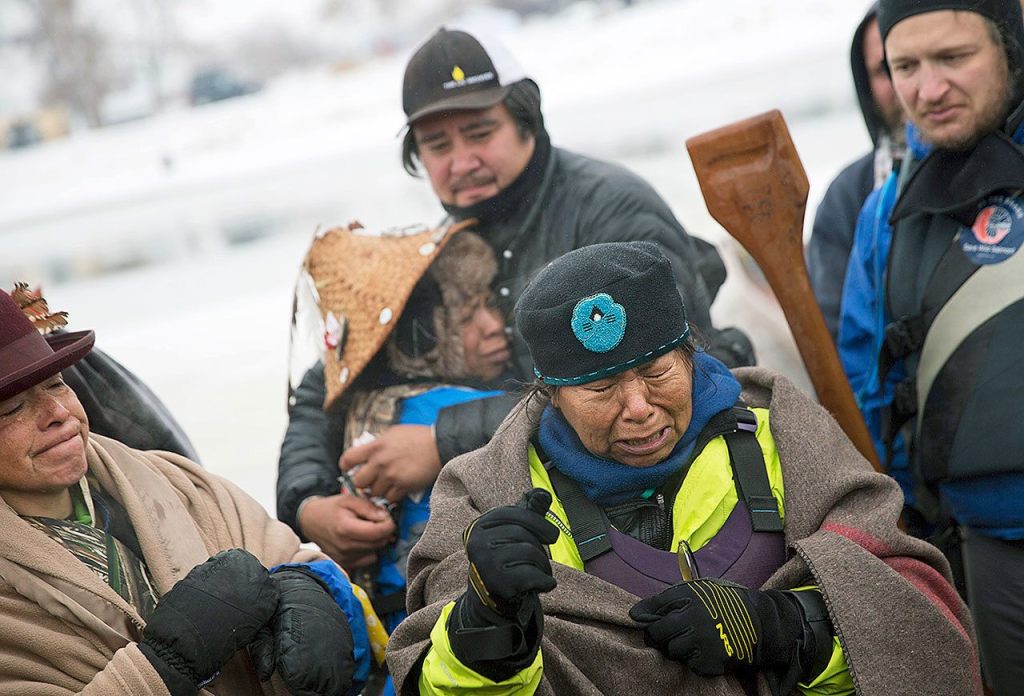 In this Thursday, Dec. 1, photo, Patty Sam Porter of Colville, Washington, right, cries after reaching shore by canoe with fellow members of the Colville Confederated Tribes, J.P. Pacodas, left, and Virginia Redstar, rear, at the Oceti Sakowin camp where people have gathered to protest the Dakota Access oil pipeline in Cannon Ball, North Dakota. The women traveled from Montana with fellow tribal members on canoe for 10 days down the Missouri river to reach the camp. (AP Photo/David Goldman)