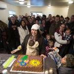 Sandy Flores cuts a cake for dozens of guests after accepting the keys to their new home from Habitat for Humanity of Snohomish County on Saturday in Everett. (Andy Bronson / The Herald)