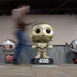 An employee at Funko, a pop culture and licensed-focused collectibles company, walks past a Jumbo Pop C3-PO and Jumbo Dorbz Starboard, left, and Ant-Man. (Andy Bronson / The Herald)