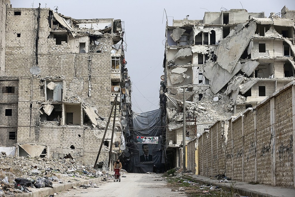 In this Dec. 5 photo, A Syrian man pushes a baby stroller as he walks past anti-sniper curtains remaining in a street in Aleppo, Syria. Aleppo shakes with explosions and gunfire day and night in both the government and rebel sides. (AP Photo/Hassan Ammar)
