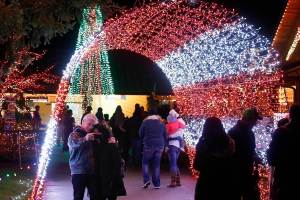 An arch of light forms a tunnel as visitors to Warm Beach Camp and Conference Center&rsquo;s annual Lights of Christmas display walk and take photos on Dec. 3. The arch leads to an area of the festival known as Joyland. (Ian Terry / The Herald)