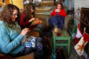 Friends Lynn Devoe (left) from Snohomish, Chloe Wilcox, from Lake Stevens, and Tina Roberts (right) from Lake Stevens sit by the warmth of a fireplace drinking coffee, talking and crafting Wednesday morning at the Living Room Coffee House at 1636 Fourth St. in Marysville. (Dan Bates / The Herald)