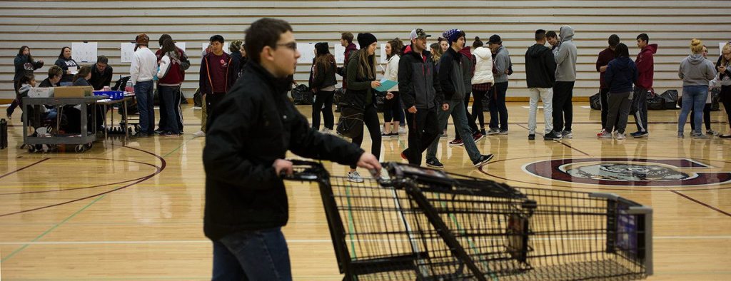 Students line up to get addresses before gathering and delivering food from Cascade High School on Wednesday, Dec. 14, 2016 in Everett, Wa. (Andy Bronson / The Herald)
