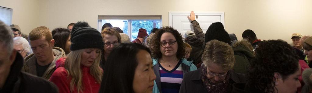 A guest blesses the front door as Ray and Sandy Flores accept the keys to their new home from Habitat for Humanity of Snohomish County on Saturday in Everett. (Andy Bronson / The Herald)