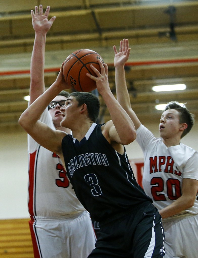 Arlington&rsquo;s Griffin Gardoski (center) goes up for a shot as he&rsquo;s guarded by a pair of Marysville Pilchuck defenders during a game at Marysville Pilchuck High School on Wednesday. (Ian Terry / The Herald)