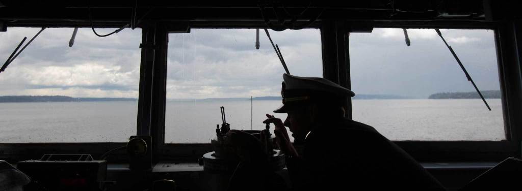 Ensign Tanner Roach takes a bearing from the bridge of the USS Gridley, the newest guided missile destroyer to be based at Naval Station Everett, as it begins heading toward Seattle for Seafair on Tuesday, Aug. 2, 2016. ( Andy Bronson / The Herald )