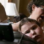 Cheryl Pyles holds her phone while her son Jessie Pyles, 7, watches a video during down time at their home in Lake Stevens. Raising Jessie, who has autism with developmental delay, a sensory - processing disorder and various other medical conditions, a labor of love with often one step forward and two steps back. (Kevin Clark / The Herald)