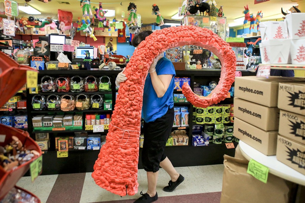 Jackie Sugita carries the now default tentacle display to the garbage Wednesday afternoon at Archie McPhees in the Wallingford neighborhood of Seattle. (Kevin Clark / The Herald)