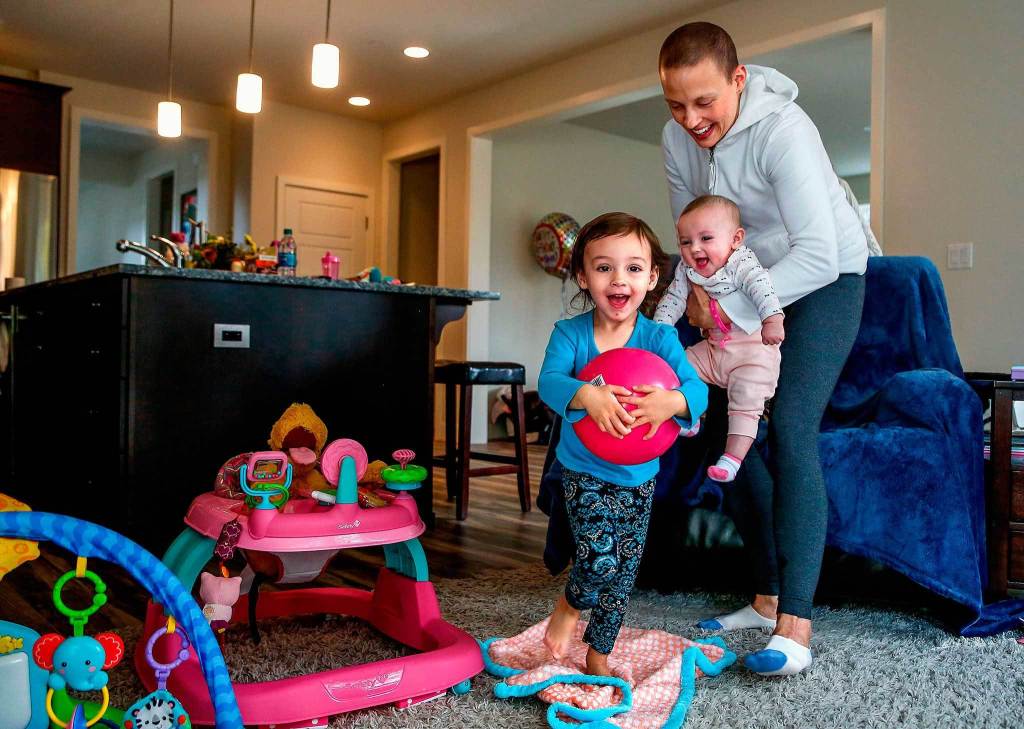 Carrying 4-month-old Haven, Apryl Roberts chases 2-year old Charlee around the house Wednesday, to the delight of all three. (Dan Bates / The Herald)