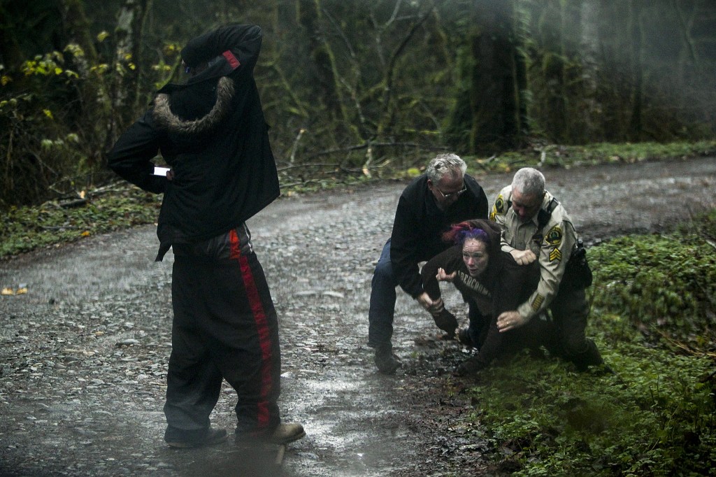 Snohomish Regional Drug and Gang Task Force commander Pat Slack and Sgt. David Casey arrest a woman with a warrant who fled upon seeing the officers on a forest road in the Mount Index Riversites community on Dec. 1. The private community has seen a recent spike in drug activity, squatting and other crime. (Ian Terry / The Herald)