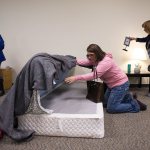 Tracy Van Beek lifts up a bed as she and other parents look for hidden drugs in a model girl&rsquo;s bedroom at Weston High on Thursday, Jan. 19, in Arlington. Van Beek and other parents and kids attended the &ldquo;Not in My House!&rdquo; event, put on by the Arlington Drug Awareness Coalition. (Andy Bronson / The Herald)