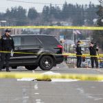 A detective (right) takes photos at the scene where a Lynnwood police officer fatally shot a man in the 19200 block of Highway 99 on Monday. (Andy Bronson / The Herald)