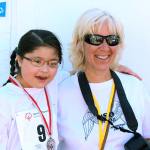 Arlington Eagles coach Sandy Catiis (right) and 8-year-old Miya Watanabe of Arlington pose together after Watanabe won a silver medal in the 200-meter dash in a Special Olympics competition in 2014. (Photo courtesy of Sandy Catiis)