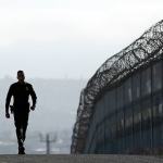 A Border Patrol agent walks near a fence separating Tijuana, Mexico, and San Diego in June. (AP Photo/Gregory Bull, file)