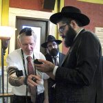 Rabbi Berry Nash (right) prays as Montana Rep. Dave Fern, R-Whitefish, wears boxes containing Torah versus called Tefillin on Wednesday, Jan. 18, in Helena, Montana. Nash was among a delegation of Orthodox Jewish rabbis from the U.S. and Canada who met with Fern and other state leaders to thank them for defending the Jewish community in Whitefish when it was threatened and harassed by white supremacists last month. (AP Photo/Matt Volz)