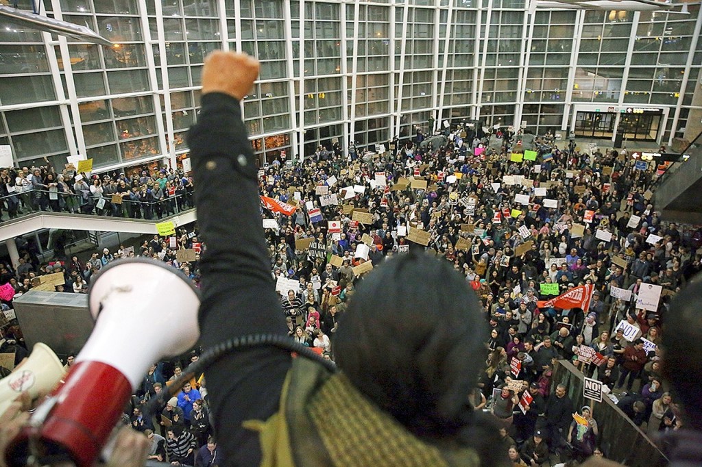 Seattle city councilwoman and socialist activist Kshama Sawant raises a fist over the crowd, as more than 1,000 people gather at Seattle-Tacoma International Airport, to protest President Donald Trump&rsquo;s order that restricts immigration to the U.S., Saturday, Jan. 28, in Seattle. The protest in Seattle was one of several across the country over the weekend. (Genna Martin/seattlepi.com via AP)