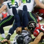 The Falcons&rsquo; Ben Garland (63) falls onto Seahawks quarterback Russell Wilson (3) for a safety during the first half of a playoff game Saturday in Atlanta. (AP Photo/John Bazemore)