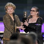 In this Jan. 25, 2015 photo, Carrie Fisher (right) presents her mother, Debbie Reynolds, with the Screen Actors Guild life achievement award at the 21st annual Screen Actors Guild Awards in Los Angeles. Reynolds&rsquo; death certificate obtained Tuesday, Jan. 10, confirms that the actress died of a stroke. (Photo by Vince Bucci/Invision/AP, File)