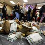 Students at Snohomish High School walk past lunchroom waste piled on the school&rsquo;s cafeteria floor during Waste Managementճ Trash on a Tarp initiative Tuesday. The program, which marked its first event in Snohomish County on Tuesday, aims to help students visualize the amount of trash created by daily activities. According to Waste Management, Snohomish County produces just under 3 million pounds of trash each day, about a third of which could have been recycled. (Ian Terry / The Herald)