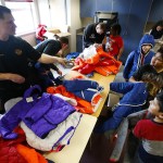 Everett Fire Department&rsquo;s Paul Gagnon (left) jokes with a group of Hawthorne Elementary School fifth-graders during a coat giveaway at the Everett school on Friday. (Ian Terry / The Herald)