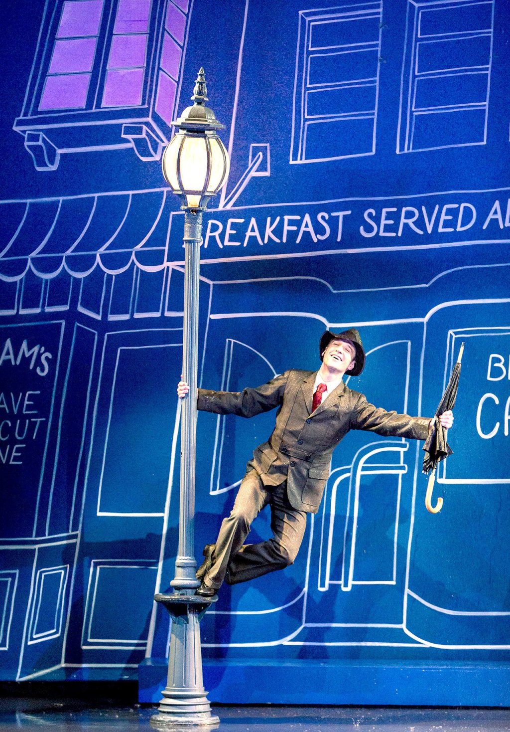 John David Scott as Don Lockwood, the role developed by Gene Kelly, sings in the rain.