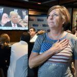 Victoria Barette from Jacksonville, Florida, holds her hand over her heart as she and other patrons watch Donald Trump take the presidential oath of office on the multiple video screens during an Inauguration Watch Party at Whiskey Jax in Marsh Landing, Florida, on Friday, Jan. 20. (Bob Self/The Florida Times-Union via AP)