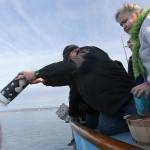 Celia Strong watches as Bryon Hollenbeck scatters the last of his father&rsquo;s ashes off the coast of Hat Island on Sunday afternoon. (Kevin Clark / The Herald)