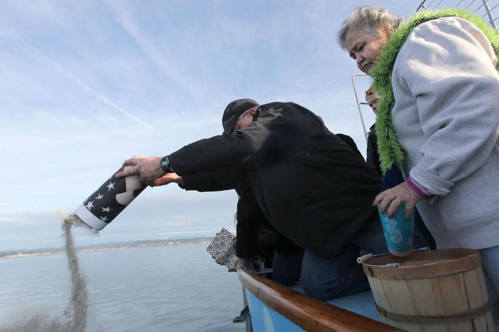 Celia Strong watches as Bryon Hollenbeck scatters the last of his father&rsquo;s ashes off the coast of Hat Island on Sunday afternoon. (Kevin Clark / The Herald)