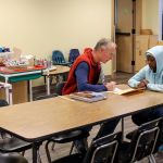 Dirk Howe (left) helps Aline Mumararungu with school work at Trinity Lutheran Church in Lynnwood on Jan. 7. (Kevin Clark / The Herald)