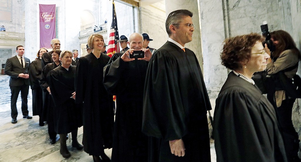 Justice Charles Wiggins (third right) playfully takes a photo as he begins to head into the House chambers for a joint session of the Legislature on Wednesday, Jan. 11, in Olympia. (AP Photo/Elaine Thompson)