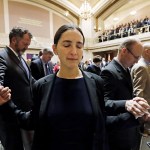 Sen. Rebecca Saldana, D-Seattle (center), holds hands with fellow legislators during an opening invocation at a joint session of the Legislature on Wednesday, Jan. 11, in Olympia. (AP Photo/Elaine Thompson)