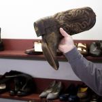A customer shows off a boot with a &lsquo;V&rsquo; shaped tear in it as he drops it off for repair at the People&rsquo;s Shoe Repair in Everett. (Andy Bronson / The Herald)