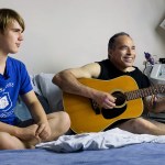 Michael Goldberg plays guitar while spending time with son Asher de Forest during one of Goldberg&rsquo;s at-home dialysis sessions in 2014. Goldberg, an associate professor at the University of Washington Bothell, passed away Dec. 26. (Photo by Quinn Russell Brown)