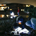 Laura Han (center), of Lynnwood, and Derek Arterburn (right), of Everett, use the glow of a flashlight to look for marine life during a beach walk after dark in Edmonds on Tuesday, Feb. 7. (Ian Terry / The Herald)