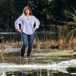 Debbie Bly-Olsen stands in her flooded yard along Lake Serene in Lynnwood on Wednesday as one of two sump pumps sprays water back into the yard. Bly-Olsen says she and her husband have gone through three pumps since the flooding started. And the water is already threatening to leak through the two-foot wall built by the previous owner. (Andy Bronson / The Herald)