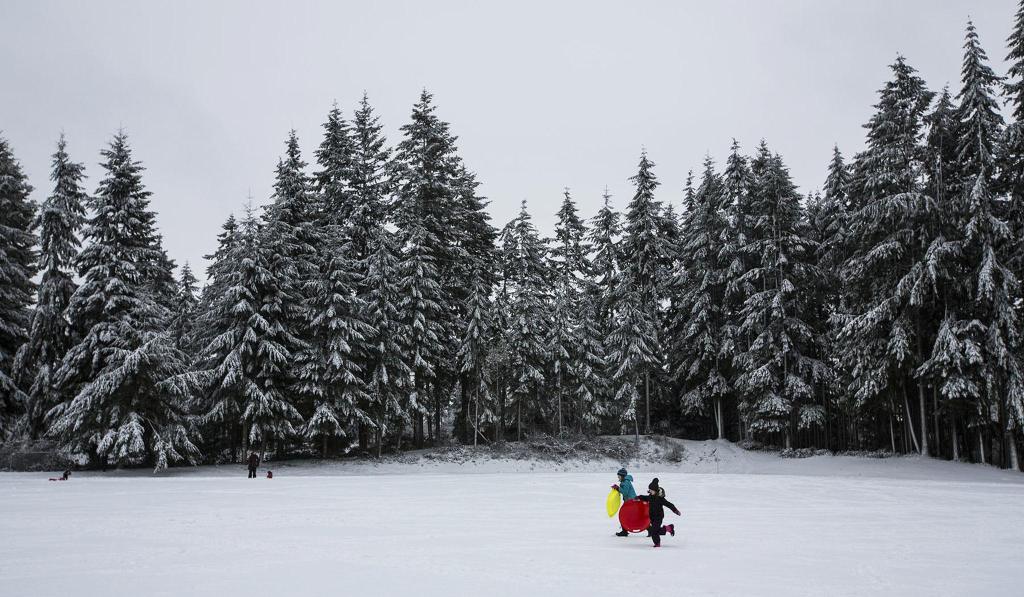 Katelynn Fitzgerald and Tegan Trefey, both 9, race through a snow-covered field at College Place Middle School on Monday in Lynnwood after a storm brought several inches, closing schools throughout the county. (Daniella Beccaria / The Herald)