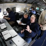 In the flight station of a Honeywell flight test plane, NASA researcher Brian Baxley (center) goes over incoming data sets with Boeing engineer Dan Boyle (center right) as NASA project manager Leighton Quon (right) looks on during a flight on Thursday from Seattle to Moses Lake to test new NextGen technologies that would allow for more streamlined consecutive landings of commercial airplanes. The technology, which improves the ability of planes to share location information, would allow for decreased spacing and improved efficiency at major airports with high traffic. (Ian Terry / The Herald)
