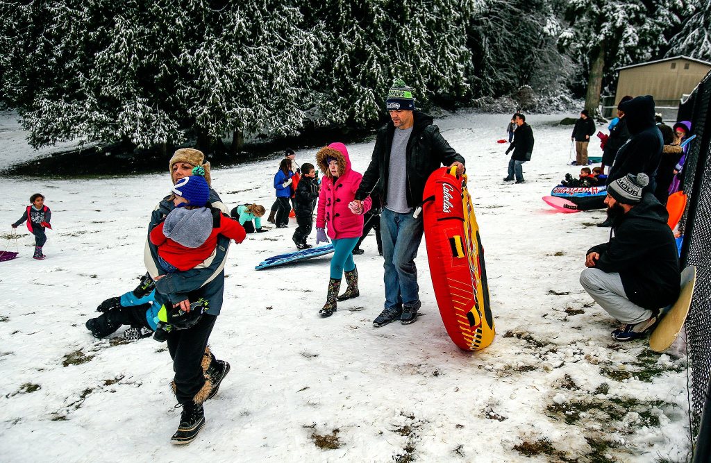 At the small park next to Pilchuck Elementary School in Lake Stevens, parents treat their kids to some sledding. (Dan Bates / The Herald)