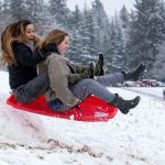 Kaitlyn Nguyen (left) and Grace McCullough scream as they hit a jump while sledding at Stanwood High School on Monday. (Andy Bronson / The Herald)