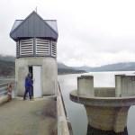 Snohomish County PUD Principal Engineer Danny Miles enters the 200-foot-tall access shaft at the Spada Lake Culmback Dam in 2001. To the the right is the morning glory spillway. (Justin Best / Herald file)