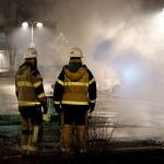 Firefighters on Monday survey the scene where riots that broke out in a predominantly immigrant Stockholm suburb after officers arrested a suspect on drug charges. (Christine Olsson/TT News Agency via AP)