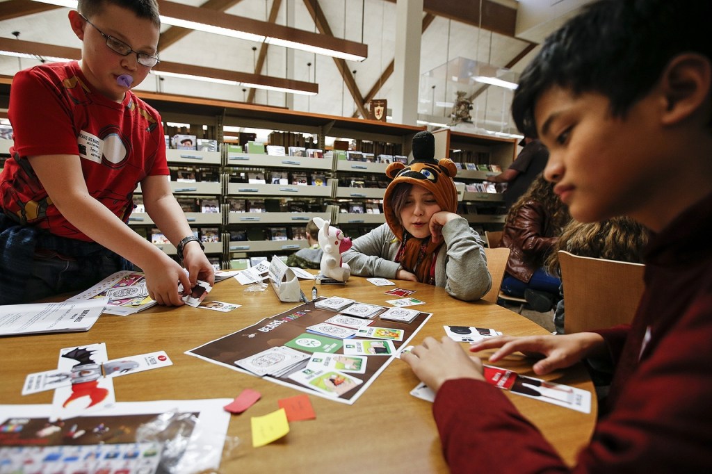 Seanus Selsor (left), 13, Jacob Zapata (center), 11, and Howard Dhave Ruado (right), 13, playtest the new game Bears vs. Babies at the Arlington Library on Wednesday. (Ian Terry / The Herald)