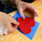 With instruction from fourth-grader Kasen Cooley, Benjamin Studley glues the heart onto a Valentine&rsquo;s Day card Thursday at Machias Elementary School. (Dan Bates / The Herald)