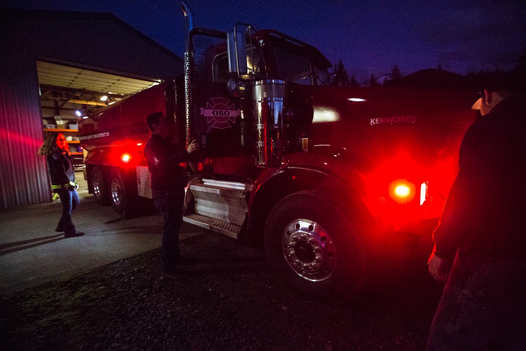 Firefighter Cyndy Olson, chaplain and firefighter Joel Johnson and fire Capt. Tim Harper check out the newly repaired firetruck at the station along Highway 530 in Oso on Tuesday, Feb. 21. (Daniella Beccaria / The Herald)