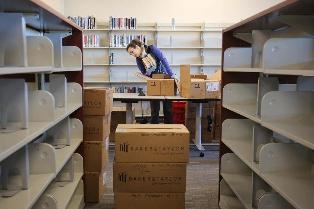 Chelsea Cooper unboxes books at the new Mariner Library in Everett on Feb. 2. The demonstration community library will carry more than 16,000 titles, and will open Saturday. (Kevin Clark / The Herald)