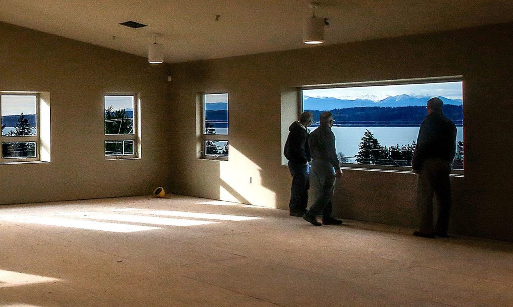 Ray Harrison (left), Mark Peterson and Jon Rice pause to take in the view from the Fellowship Room upstairs in Camano Chapel&rsquo;s new Saratoga Hall. Harrison is a member of the administrative board and his role is overseeing facilities. Peterson is the facilities director as well as project manager. Jon Rice is the church administrator. The Fellowship Room is fire-approved for 450 people. (Dan Bates / The Herald)