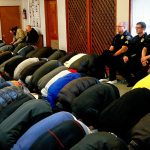 Prior to Chief Tom Davis giving a talk Friday, Lynnwood police officers sit along a wall in the back during prayers at Evergreen Islamic Institute in Lynnwood. From left, the three officers are Sgt. Cole Langdon, Deputy Chief Jim Nelson and Sgt. Sean Doty. (Dan Bates / The Herald)