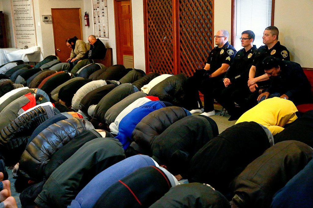 Prior to Chief Tom Davis giving a talk Friday, Lynnwood police officers sit along a wall in the back during prayers at Evergreen Islamic Institute in Lynnwood. From left, the three officers are Sgt. Cole Langdon, Deputy Chief Jim Nelson and Sgt. Sean Doty. (Dan Bates / The Herald)