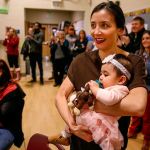 While Jerome Aparis finishes his presentation and gathers his gear, his wife, Lea Aparis, and daughter, 9-month-old Malaya, watch from a corner of the Emerson Elementary gymnasium. (Dan Bates / The Herald)